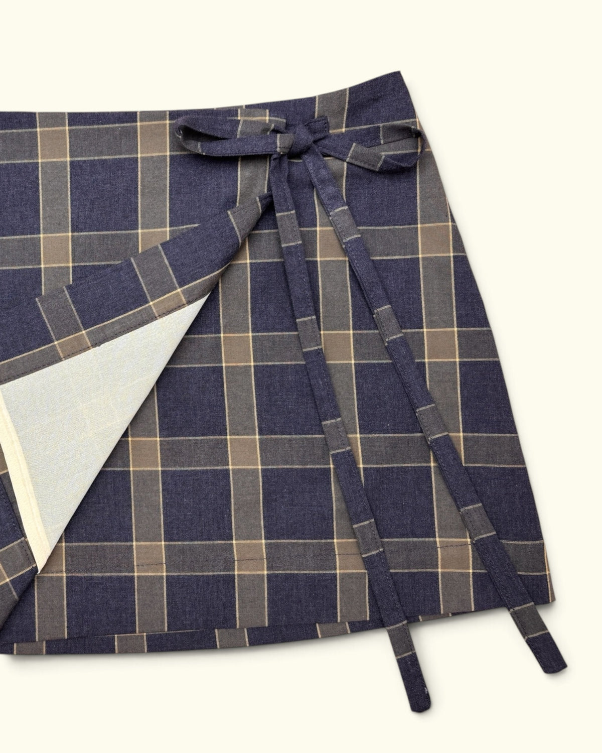 Close-up of the Tartan wrap skirt by Kazuki showing the side tie and inner wrap panel