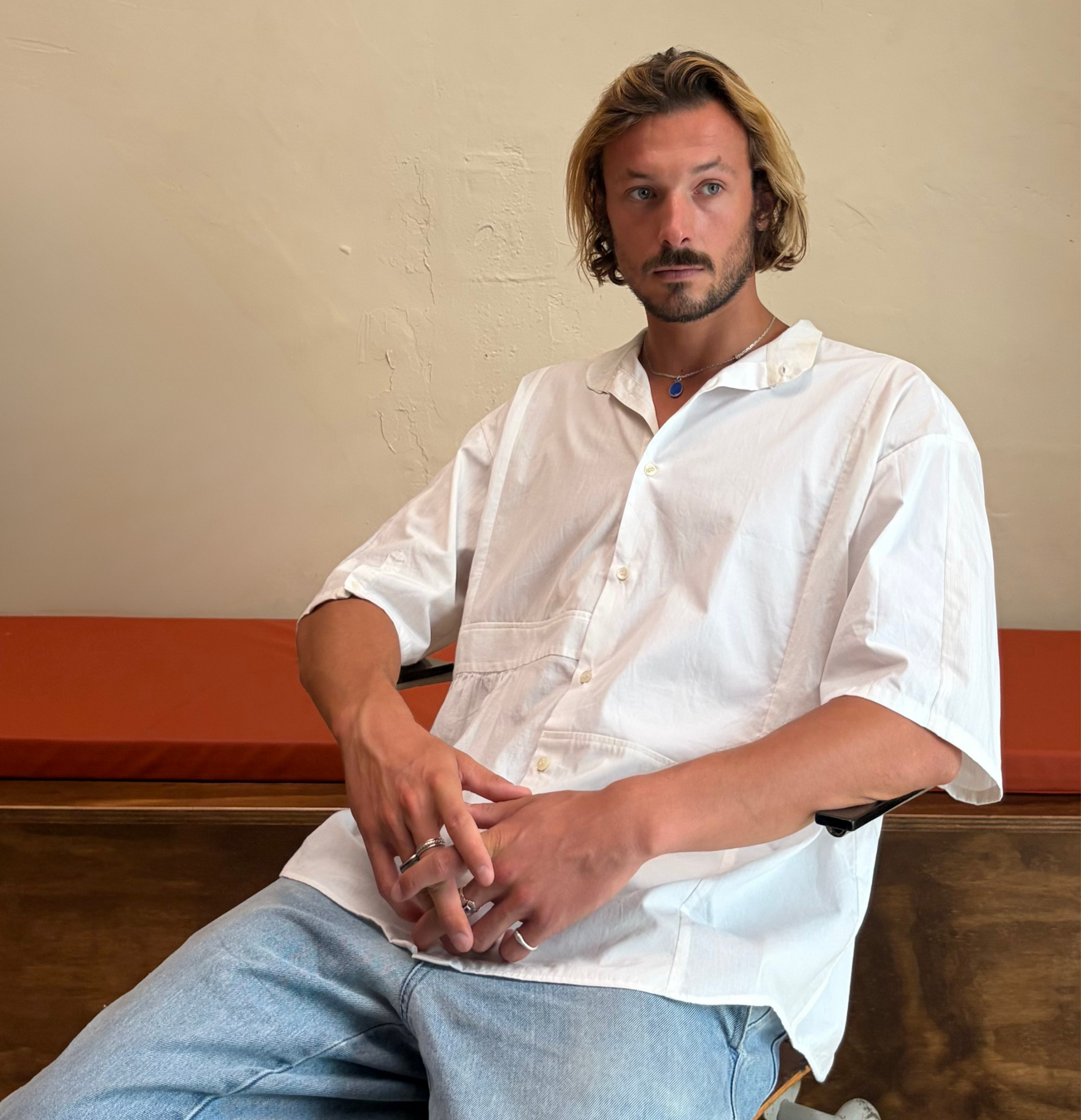 Model wearing The Blank Canvas One white upcycled patchwork shirt by Kazuki, seated view